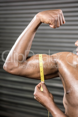 Shirtless man measuring biceps