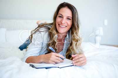 woman lying on her bed writing in a book