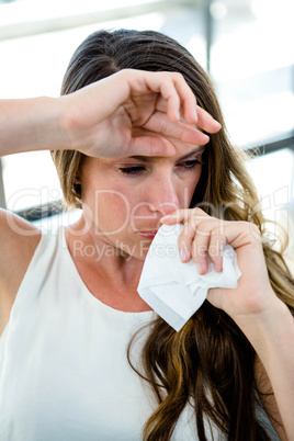 sick woman blowing her nose into a tissue