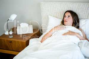 sick woman lying in bed looking unwell