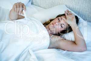sick woman in bed taking her temperature