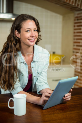 Young woman using digital tablet and coffee mug on worktop