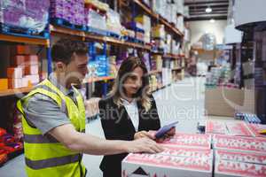 Warehouse manager and worker looking at tablet