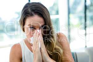 sick woman blowing her nose into a tissue