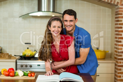 Couple embracing while checking the recipe book