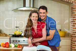 Couple embracing while checking the recipe book