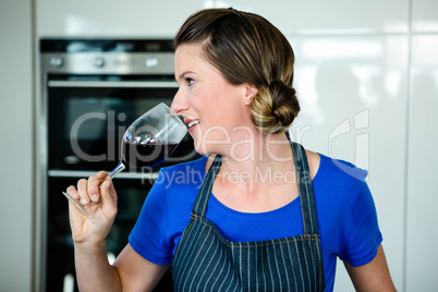 smiling woman cooking on the stove top and drinking red wine