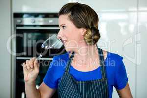 smiling woman cooking on the stove top and drinking red wine