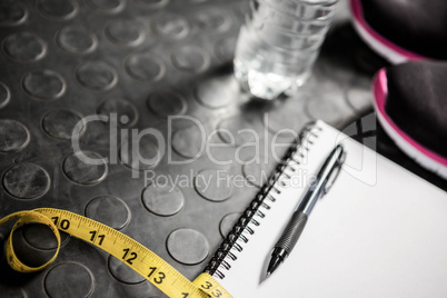 Notepad, measuring tape, shoes and bottle
