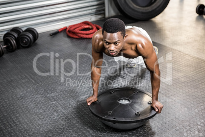 Muscular man doing push up on bosu ball