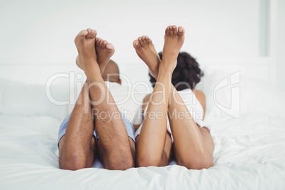 Rear view of couple on bed with raised legs
