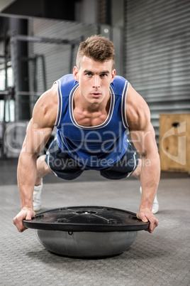 Muscular man doing push up on bosu ball