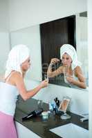 woman applying face powder in the bathroom mirror
