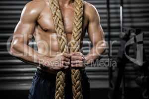 Shirtless man with battle rope around neck