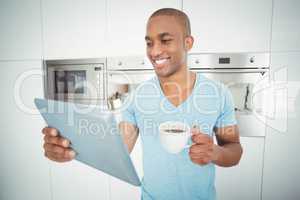 Smiling man using tablet and holding coffee