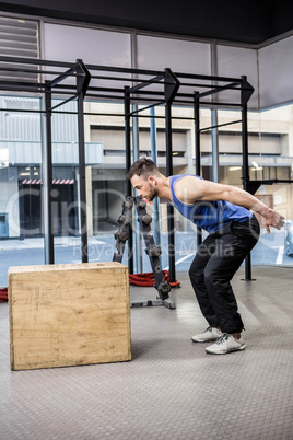 Muscular man jumping on wooden block