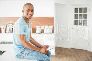 Smiling man using tablet in the kitchen