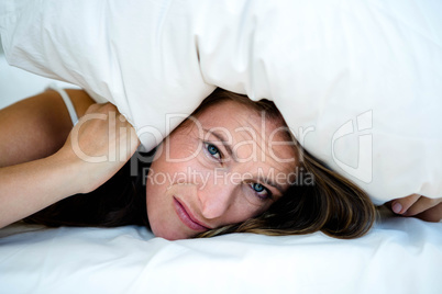 anxious woman hiding under a pillow
