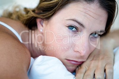 woman lying with her head on her hands looking sad