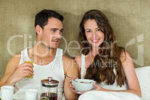 Young couple having breakfast on bed