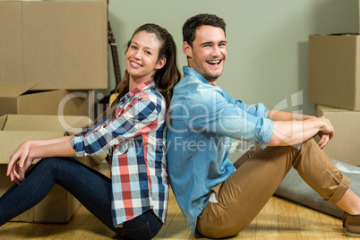 Young couple sitting back to back in their house