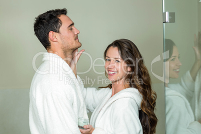 Woman applying moisturizer on manâ€™s face