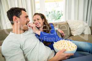 Young couple eating popcorn on sofa