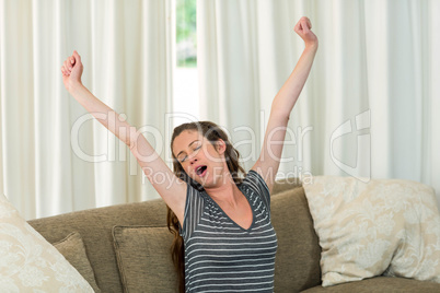 Young woman yawning and stretching her hands
