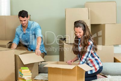 Young couple unpacking carton boxes in their new house