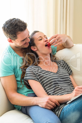 Man feeding a strawberry to woman