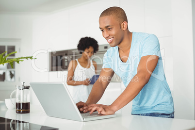 Handsome man using laptop in the kitchen