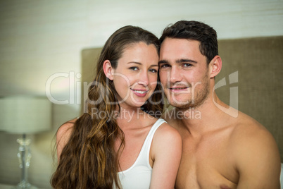 Couple sitting on bed and looking at camera