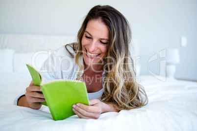 smiling woman lying on her bed reading