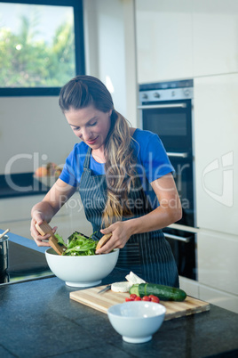 smiling woman tossing a salad for dinner