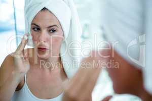 woman applying face cream in the mirror