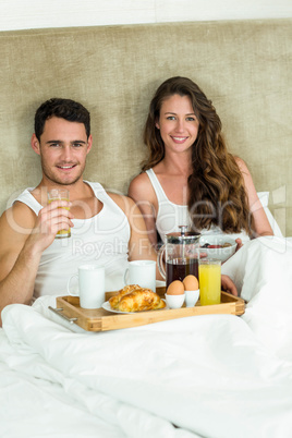 Young couple having breakfast on bed