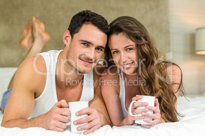 Young couple having cup of coffee on bed