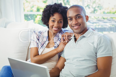 Happy couple using laptop on the sofa