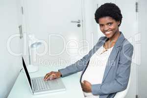 Pregnant businesswoman working on laptop