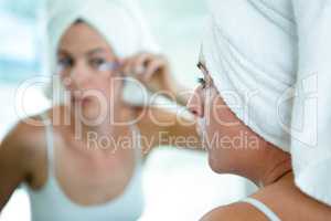 woman applying mascara in the mirror
