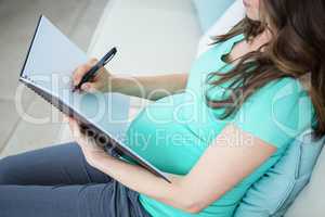 Pregnant woman writing on document