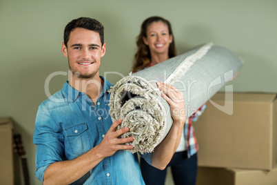 Happy couple carrying rolled up rug