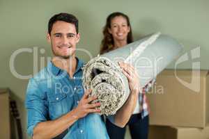 Happy couple carrying rolled up rug