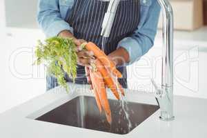 Mid section of man washing carrots