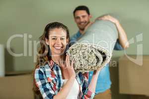 Happy couple carrying rolled up rug
