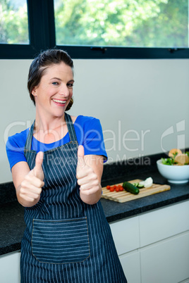 smiling woman preparing vegetables for dinner and giving a thumb