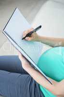 Pregnant woman writing on document