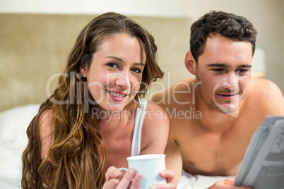 Young couple reading newspaper on bed