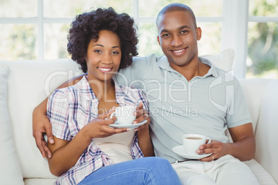 Happy couple on the sofa drinking coffee