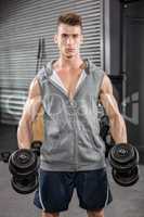 Muscular man with grey jumper holding dumbbells